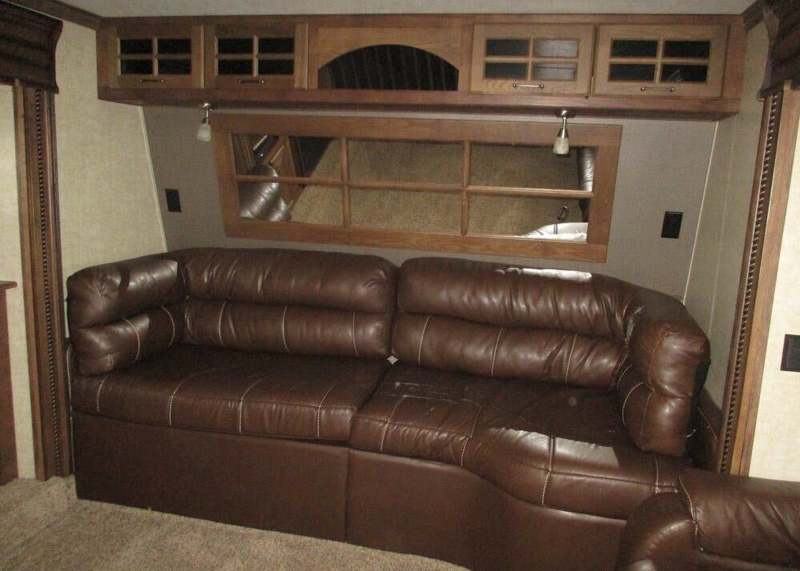 Original couch in the living room with dark wood trim and dirty gray walls.